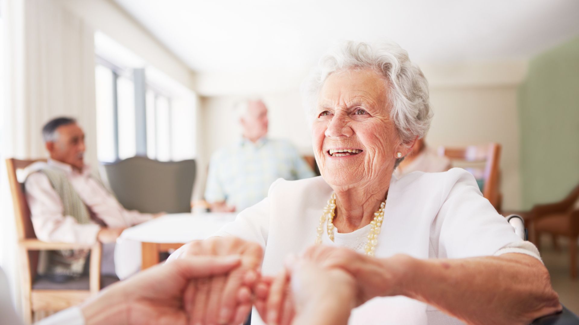 Mujer mayor muy contenta cogida de las manos de otra persona