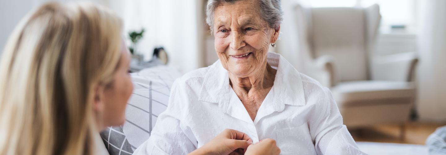 Mujer mayor sonriendo y hablando con una cuidadora