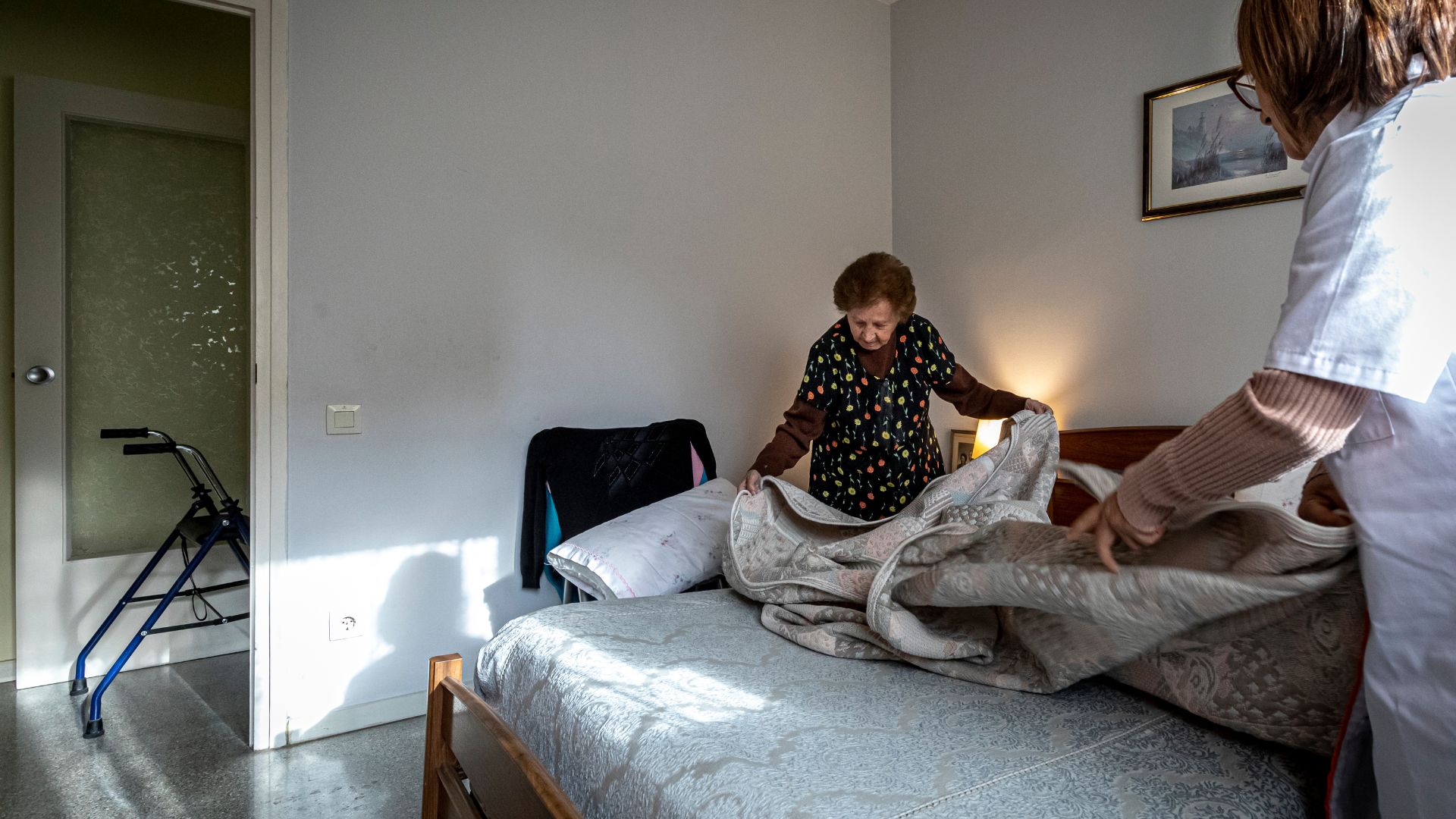 Profesional de Suara ayudando a hacer la cama a una persona mayor en el domicilio