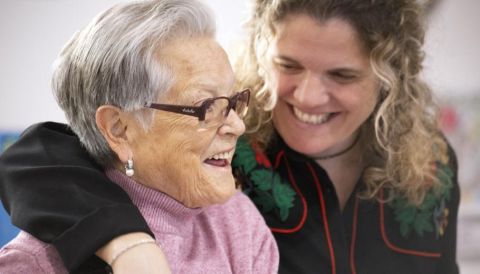 directora de Colònia Güell abrazando y riendo con una persona atendida