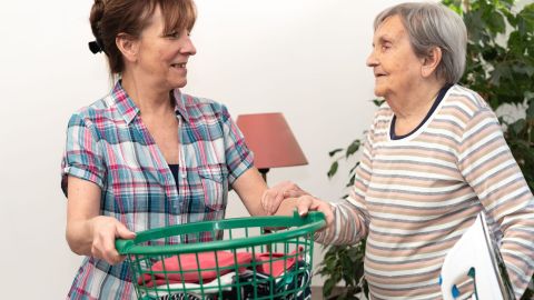 Cuidadora ayudando con la limpieza de la ropa a una mujer mayor en el domicilio