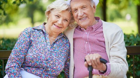 Dos personas mayores felices sentados en un banco de un parque